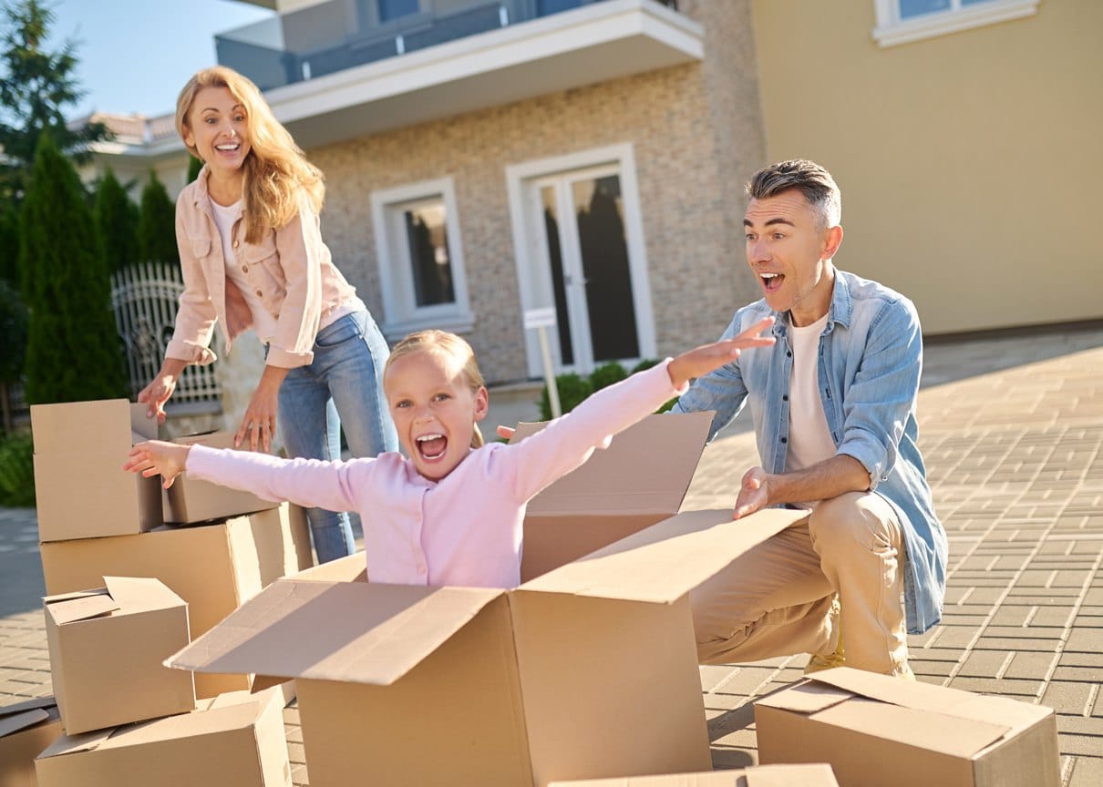 Familie packt vor ihrem neuen Zuhause Umzugskartons aus