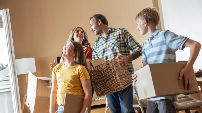 Familie trägt Umzugskartons ins neue Zuhause, Zwischenfinanzierung beim Hauskauf